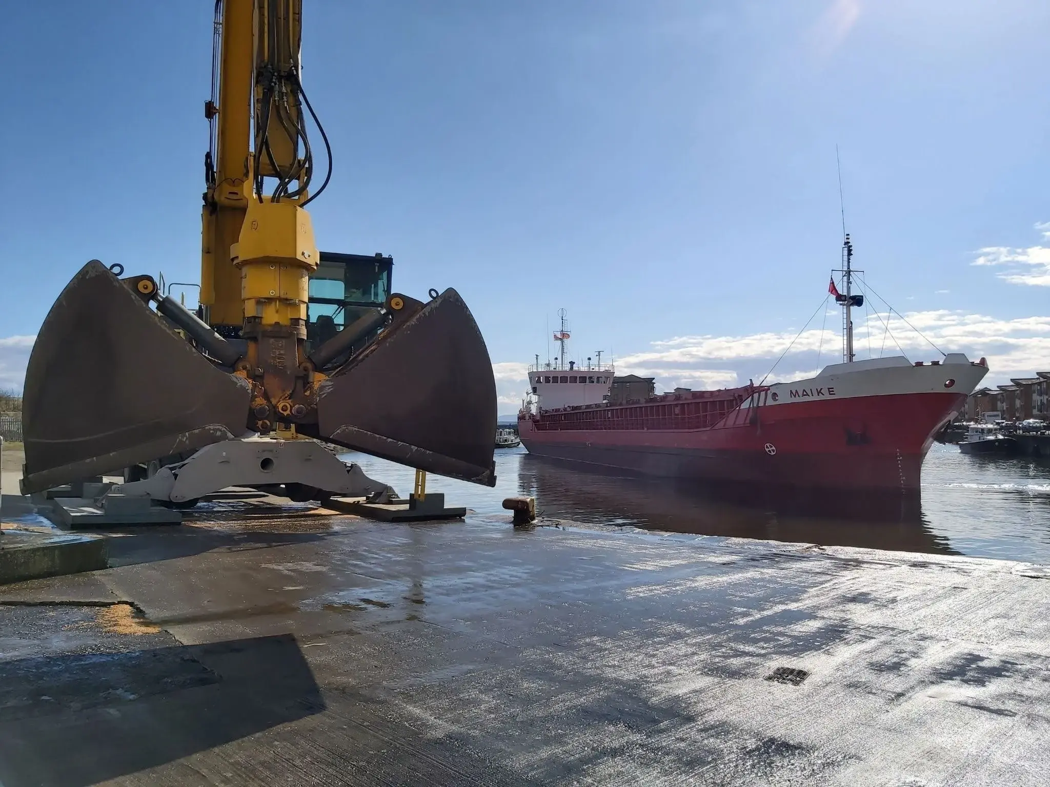 A UK shipping agent coordinating cargo operations at a port with a vessel and a crane.