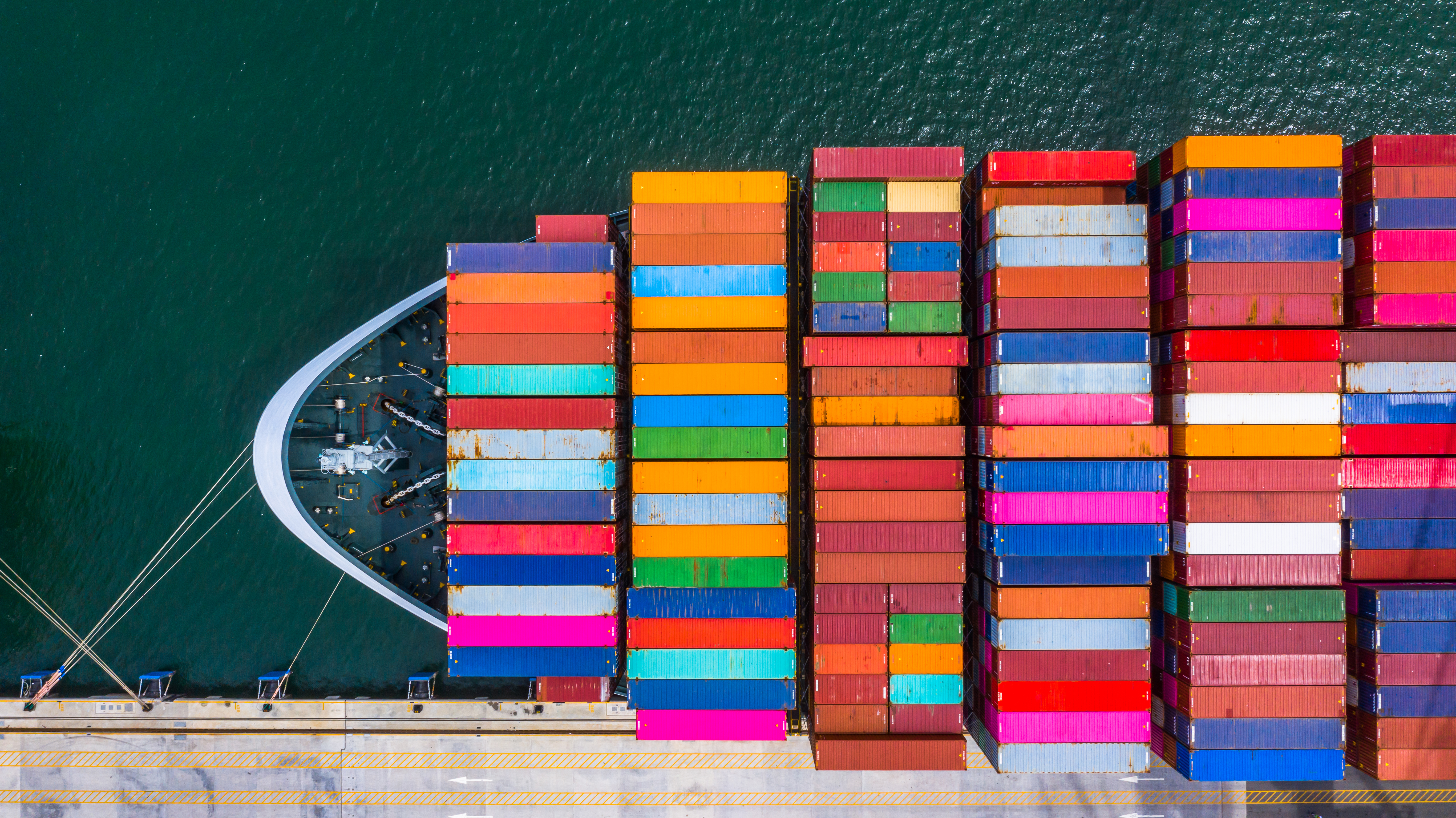 A container ship loaded with colourful groupage freight containers moored at a commercial port.