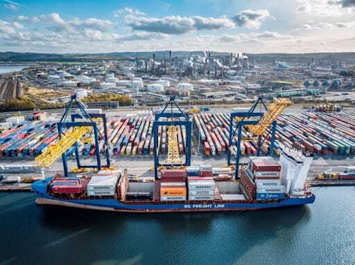 A container ship at a UK port highlighting cargo delays and container handling operations.